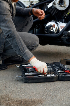 Crop mechanic choosing tool near motorbike