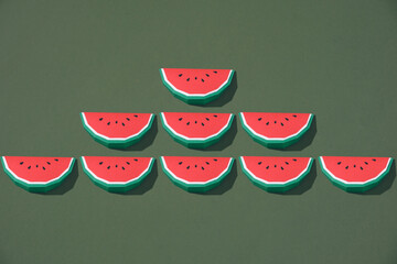 Slices of watermelon made with paper on green background.