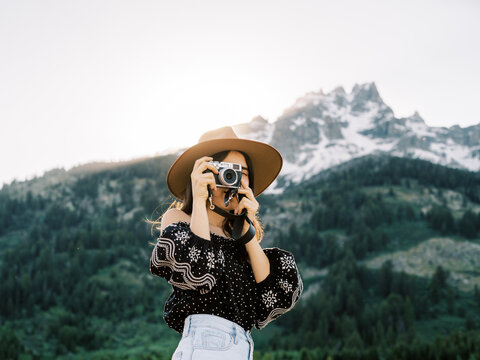 Woman taking picture in front of mountain range