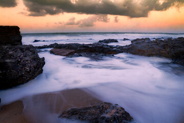 Wake of sea foam left by the waves and the wind. Long exposure seascape during a sunset.