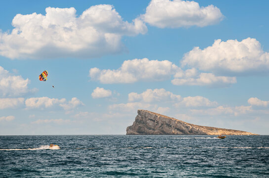 Person parasailing over sea in summer