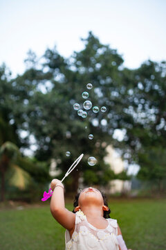 Little girl blowing bubbles at outdoors