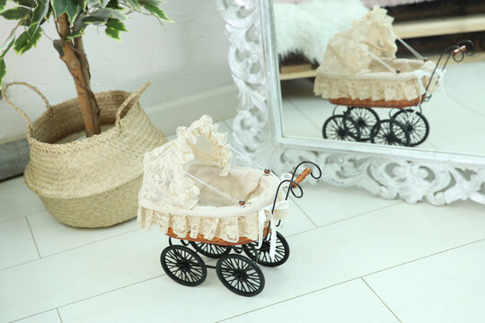 Baby carriage is in the room on the floor by the mirror