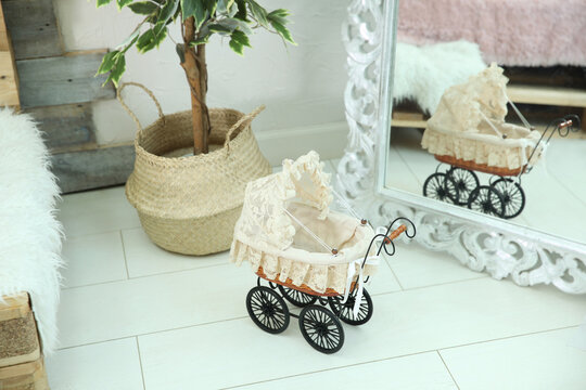 Baby stroller with lace stands in a room with a reflection in the mirror