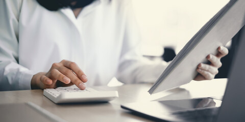 Close-up of a businesswoman using a calculator to audit the company's budget. Tax information is calculated by accountants