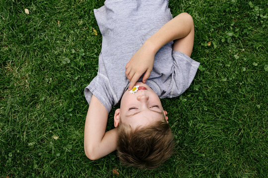 A young boy is lying on the green grass.
