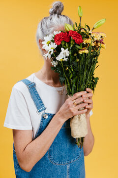 Anonymous mature female smelling flowers