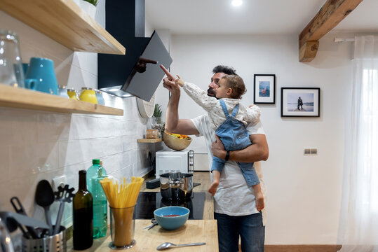 Father and toddler cooking together in kitchen