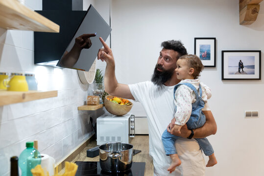 Father and toddler cooking together in kitchen