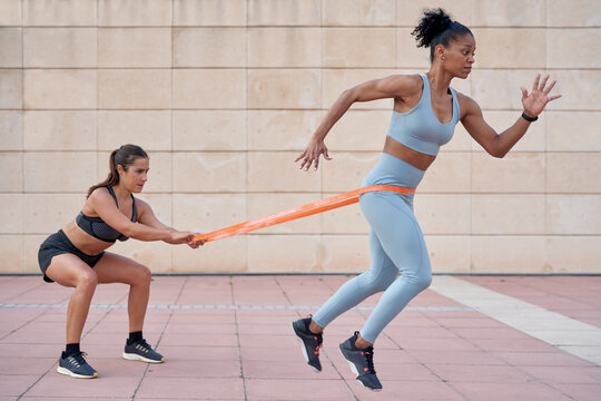 Diverse sportswomen exercising with resistance band together