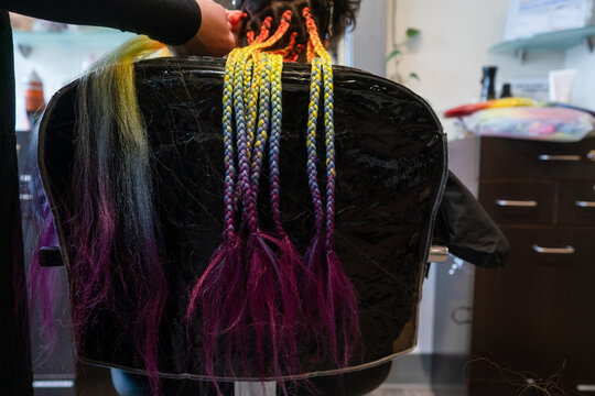 Girl in salon chair gets rainbow braids installed 