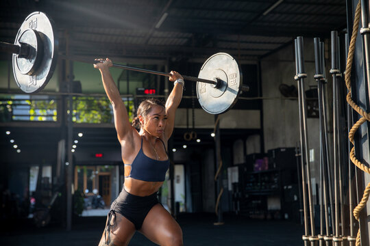 Muscular female athlete lifting heavy weights at gym - Powered by Adobe