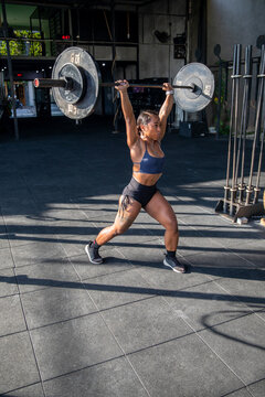 Muscular female athlete lifting heavy weights at gym 