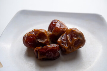 Arabic food dates are placed on a white plate on a white background