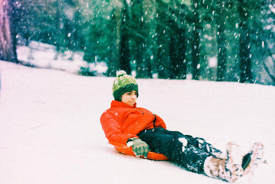 Boy riding sledge on snowy slope