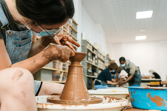 Woman crafting clay vase during pottery lesson - Powered by Adobe