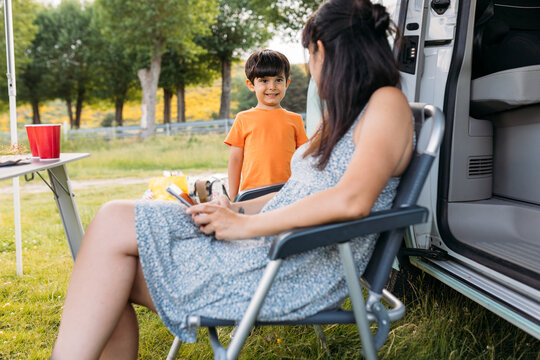Unrecognizable mother with smartphone interacting with son in countryside