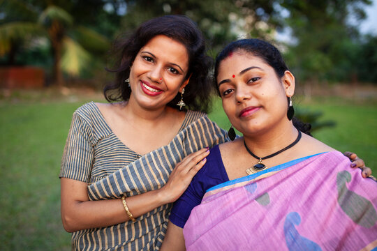 Two Indian woman wearing sari and holding each other