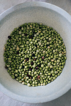 Shelled green beans in plastic bowl on table