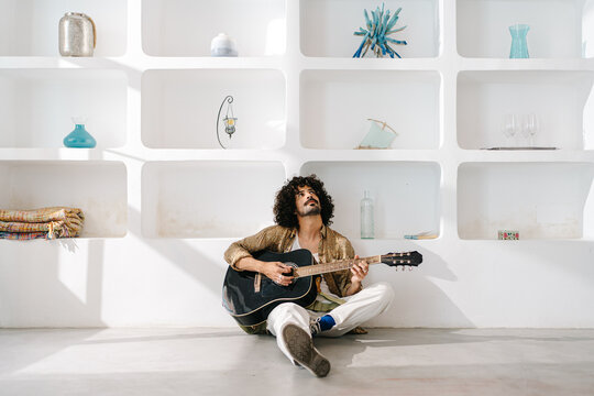 Young man with guitar composing song at home