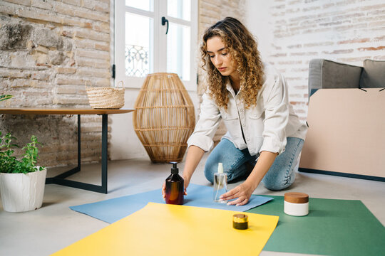 Photographer arranging beauty products on colorful paper sheets