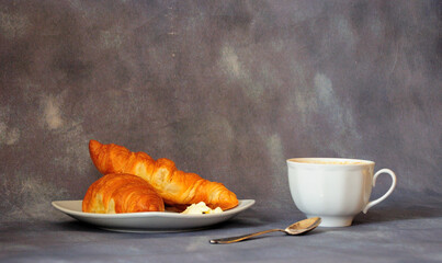 Delicious breakfast, two fresh butter croissants and a cup of cappuccino.