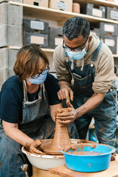 Black man teaching woman during pottery class