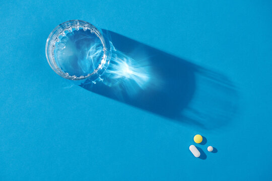 Color Medical Pills And Glass Of Water On Light Blue Background,