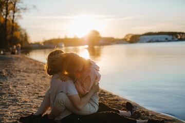 guy and girl embrace at sunset
