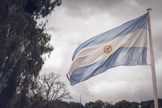 bandera Argentina flameando en m&aacute;stil gris con fondo de cielo azul