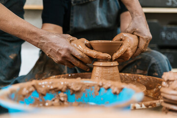 Anonymous hands of two potters creating on the potter's wheel