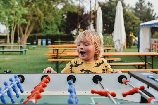 A blond kid happy to win in a table soccer 