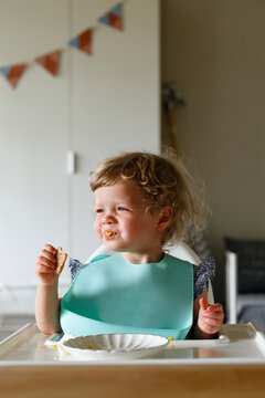 Happy baby eating breakfast at table