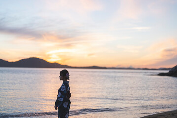 夕暮れの海にいる浴衣の女性