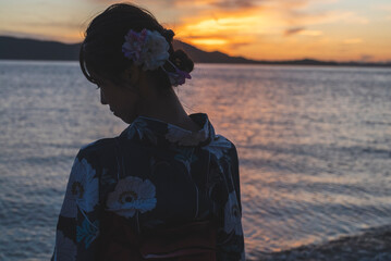 夕暮れの海にいる浴衣の女性