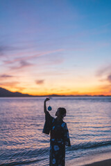夕暮れの海にいる浴衣の女性