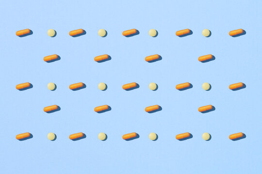 Creative layout of colorful pills and capsules on blue background.