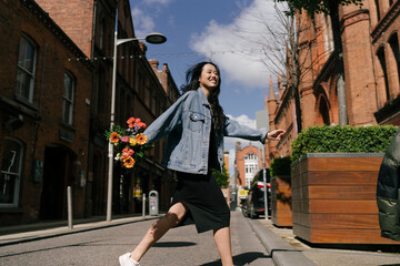 Happy Asian Woman Crossing the Street with Flowers