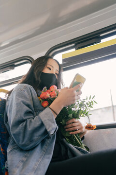 Woman on the Bus with Phone and Flowers