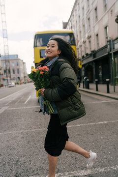 Happy Asian Woman Crossing the Street with Flowers
