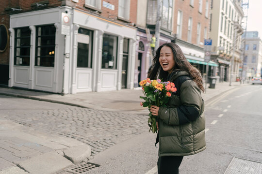Happy Asian Woman Crossing the Street with Flowers