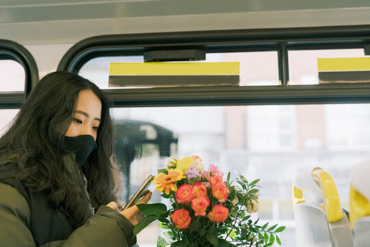 Woman on the Bus with Phone and Flowers