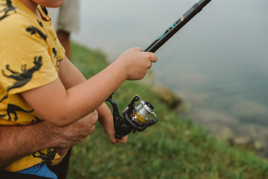 A close-up of hands of father and son holding the rod