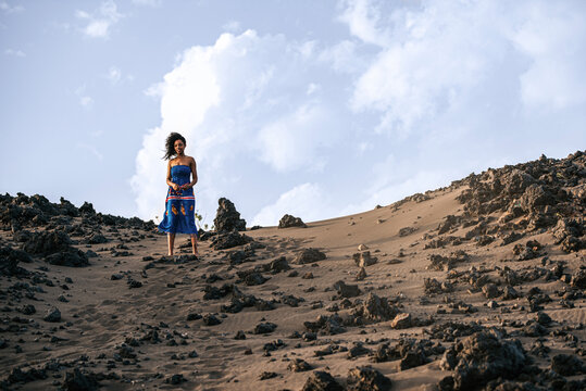 African woman standing on volcanic sand dune on beach