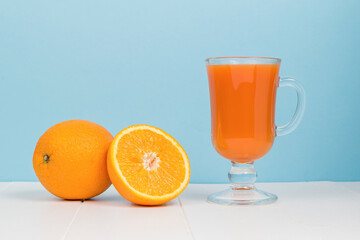 A glass glass with a smoothie on a white table on a blue background.