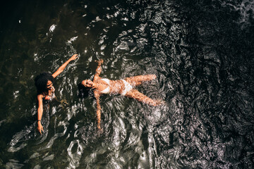 African black women swimming at lake with waterfall