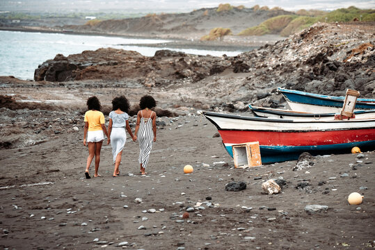 Black three women walking near boat and seashore