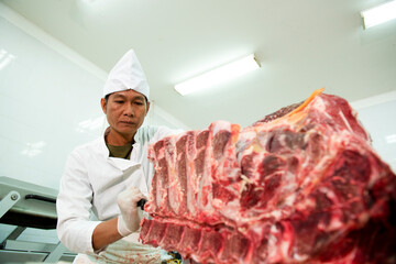 Japanese Wagyu Meat Industry A butcher cuts raw meat with a knife at a table in a slaughterhouse. Wagyu Beef in Asia