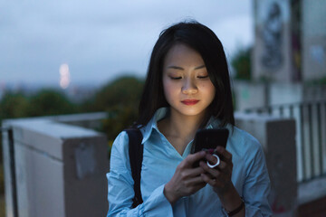 Young woman looking at phone at night in street 