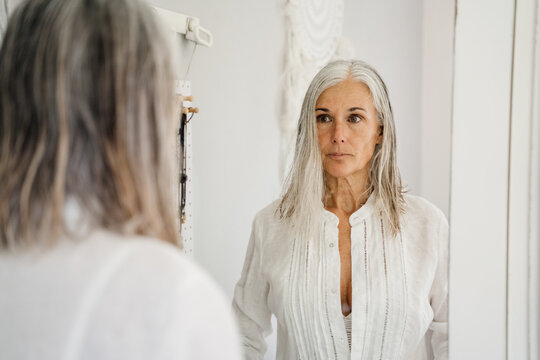 Mature woman looking at herself in table mirror